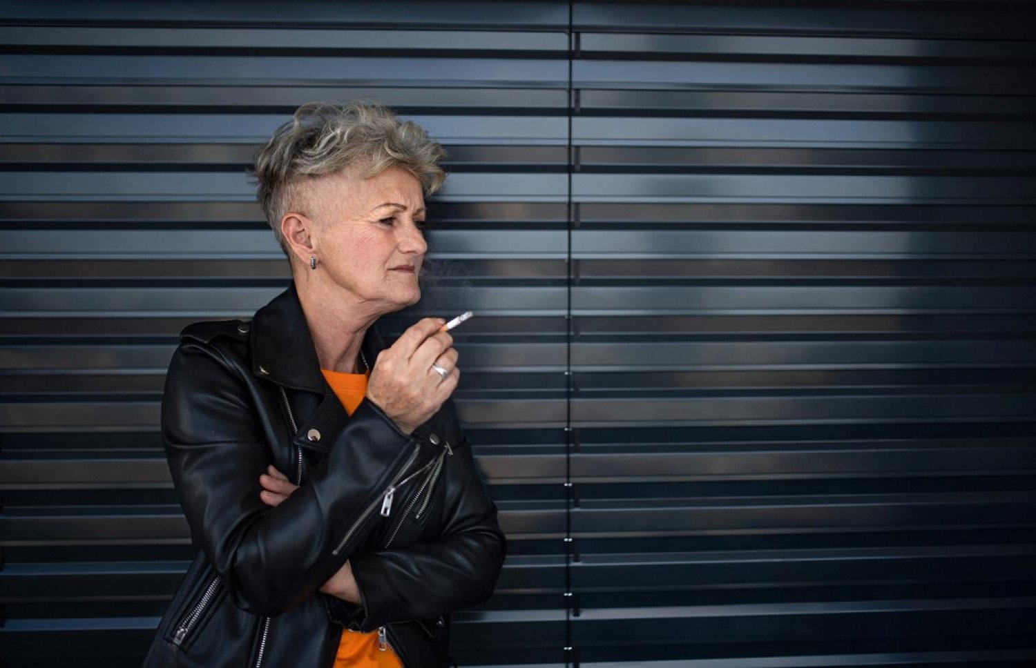 Woman leaning against a wall smoking a cigarette, showing stress-driven smoking behaviour